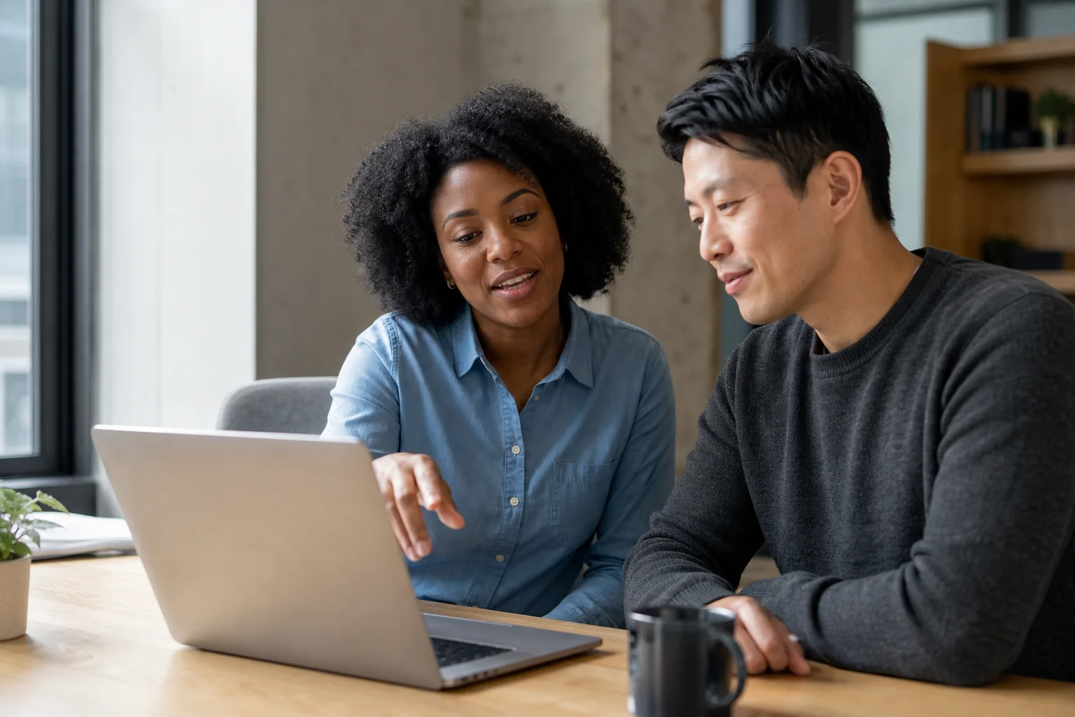 Colleagues working side by side on a laptop during an onboarding conversation.
